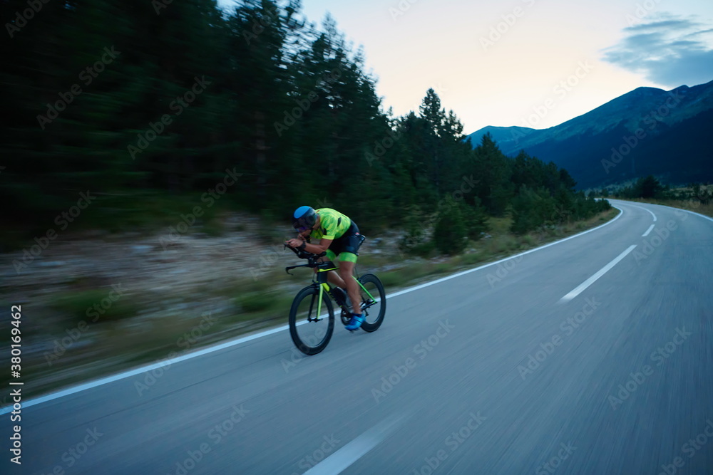 Naklejka premium triathlon athlete riding bike at night