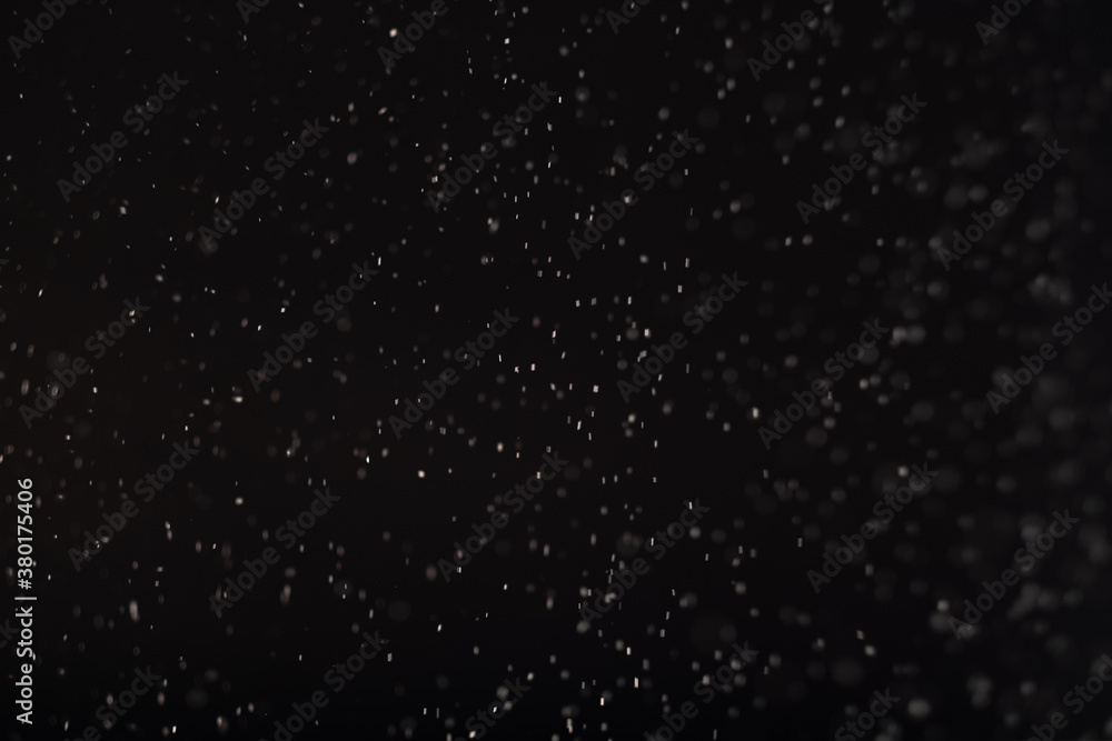 Snow background. Defocused falling white ice flakes isolated on black. Dark winter night sky. New Year holidays blizzard. Blur particles decorative pattern abstract wallpaper.