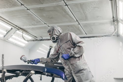 Painter working and painting pieces of a car in paint garage. photo