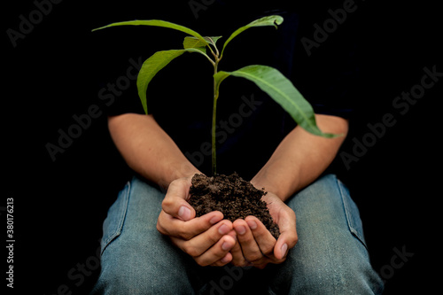 Shot of human hands holding a plant in his hand isolated over black background. Concept of Caring nature & Care for Mother Nature. photo