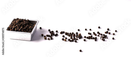 Black pepper in a white ceramic cup on a white background