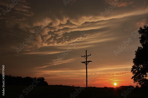 stormy sunset with clouds and power lines west of Nickerson Kansas USA that's bright and colorful out in the country.
