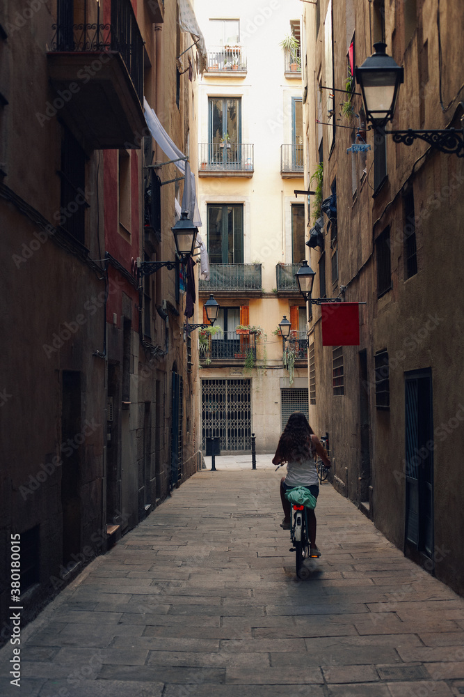 Young girl riding her bike by the old town of Barcelona city