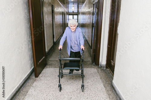 Elderly woman using an adult walker to walk inside her apartment building