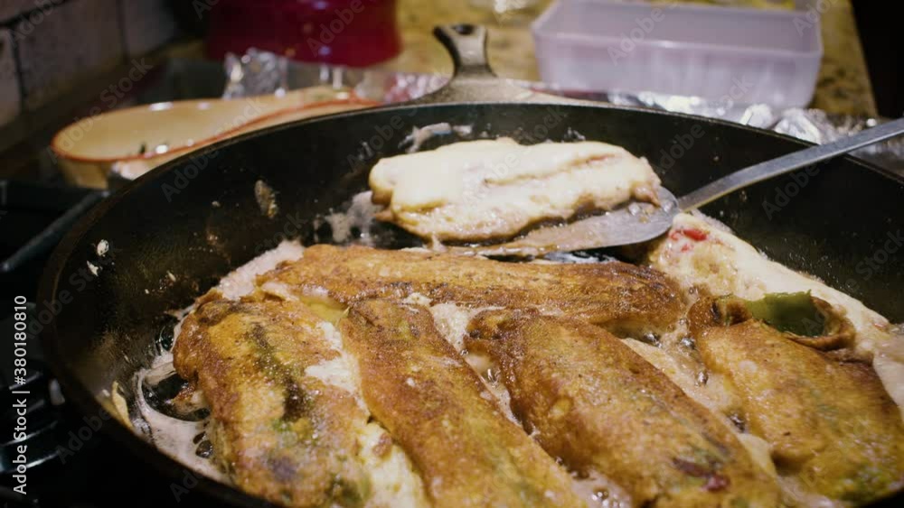 Frying chile rellenos in a cast iron skillet. The delicious cheese stuffed green peppers are a staple of Southwestern New Mexican cuisine. Frying chile rellenos in a cast iron skillet. The delicious cheese stuffed green peppers are a staple of Southwestern New Mexican cuisine.