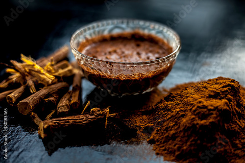 Close up shot of fresh raw revand chini roots and its paste in a glass bowl along with some raw powder on a wooden black surface. photo