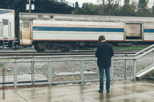 Back of Man Waiting for Train in the Rain photo