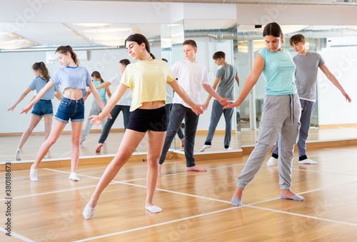 Fototapeta Naklejka Na Ścianę i Meble -  Diligent friendly smiling teenagers learn dance movements in dance class