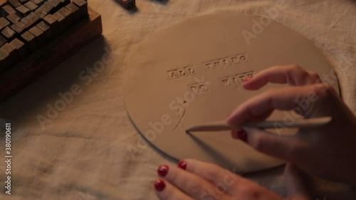 Printing letters on clay plates in the workshop. Decorative tableware made of handmade ceramics close-up. photo