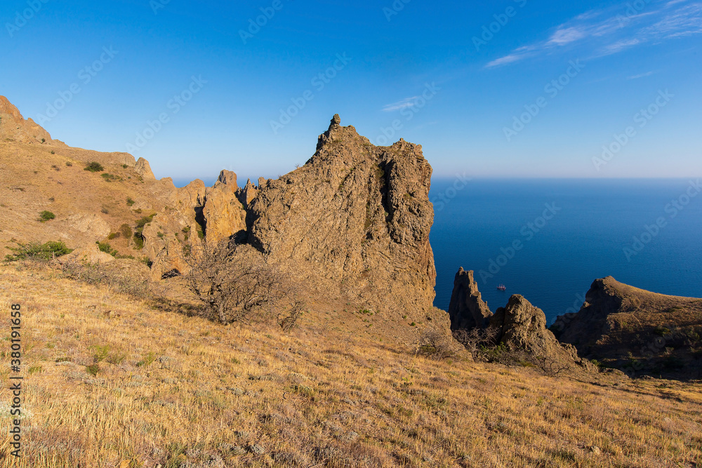 The peaks of the mountains of the Karadag reserve against the background of the sea on a summer day. Crimea.