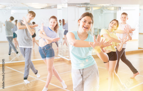 Fototapeta Naklejka Na Ścianę i Meble -  Teenagers in dance hall studying new movements, smiling and having fun