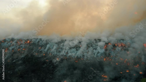 Aerial view at fire at garbage dump, burning pollutes the environment. Ecological catastrophe and destruction of nature, large fire area, camera moves into the distance