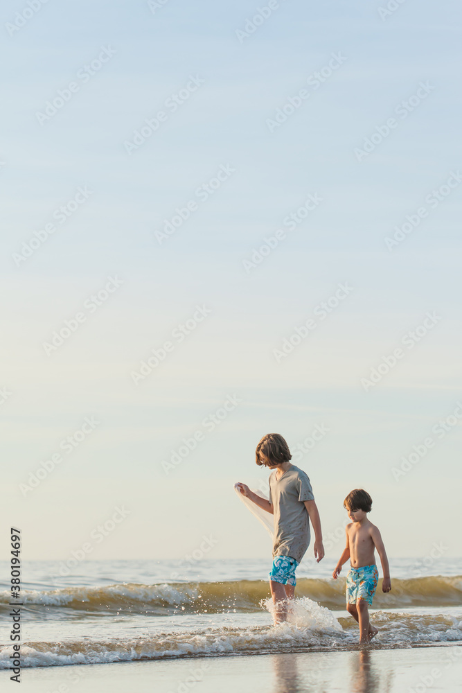 Two boys standing in the ocean looking for jellyfish Two boys standing in the ocean looking for jellyfish