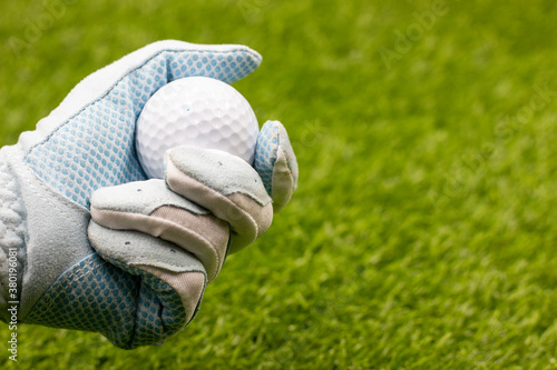 Golfer is holding golf ball on green grass background