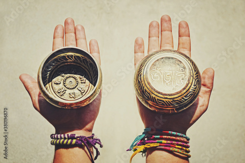 Two (2) hands holding and showing both sides of decorated Tibetan Singing Bowls photo