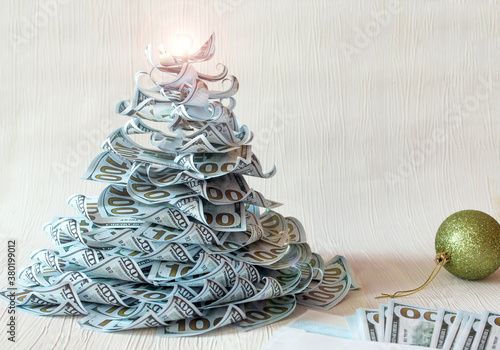  Christmas tree made of paper dollar bills on a white background with a green Christmas ball and banknotes,-the concept of wishes for financial well-being and fulfillment of wishes