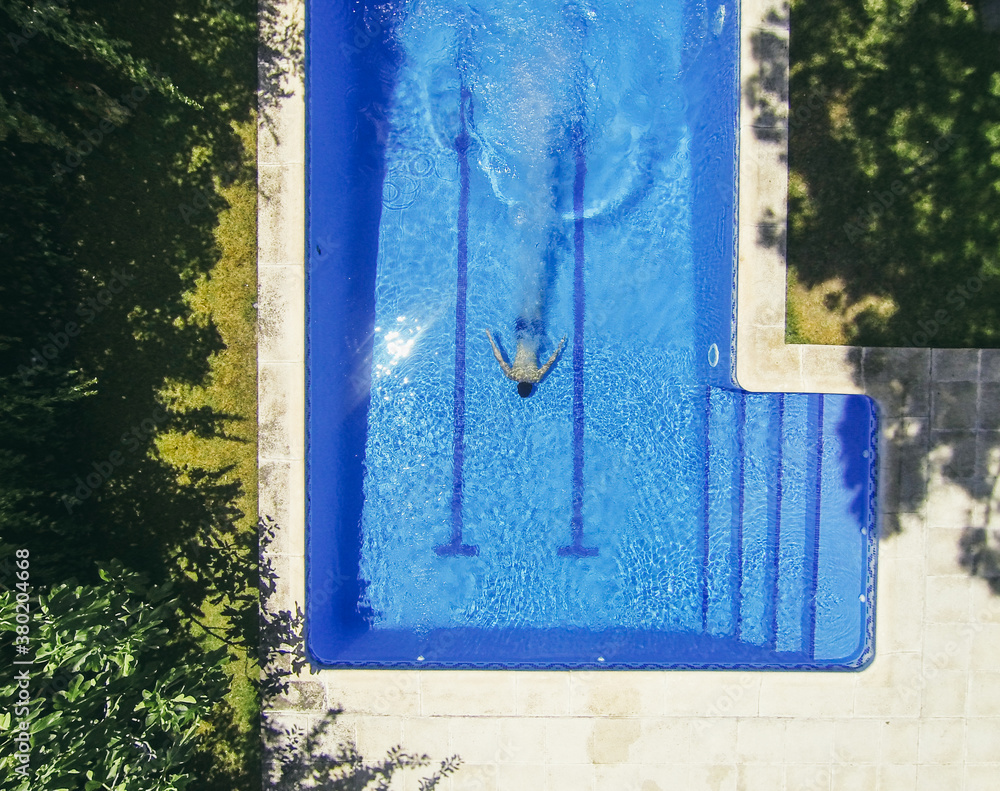 Aerial view of young man in a pool during a sunny day Aerial view of young man in a pool during a sunny day