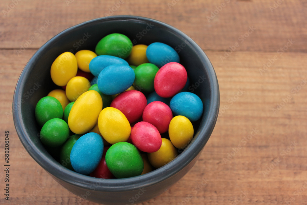 Colorful jelly beans candies in a bowl on wooden background. Sweet holiday treats for kids Colorful jelly beans candies in a bowl on wooden background. Sweet holiday treats for kids