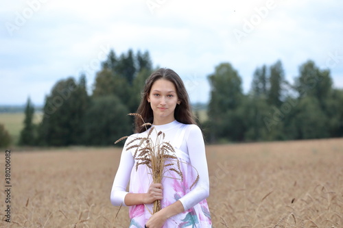 Young girl in national costume in a field with wheat