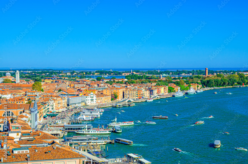 Aerial panoramic view of Venice historical city centre, Riva degli Schiavoni waterfront with moored ships and boats, lively promenade of St. Mark Basin Venetian lagoon, Veneto Region, Northern Italy.