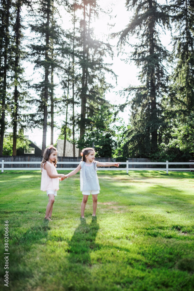 Young twin sisters playing in the front yard of their home Young twin sisters playing in the front yard of their home