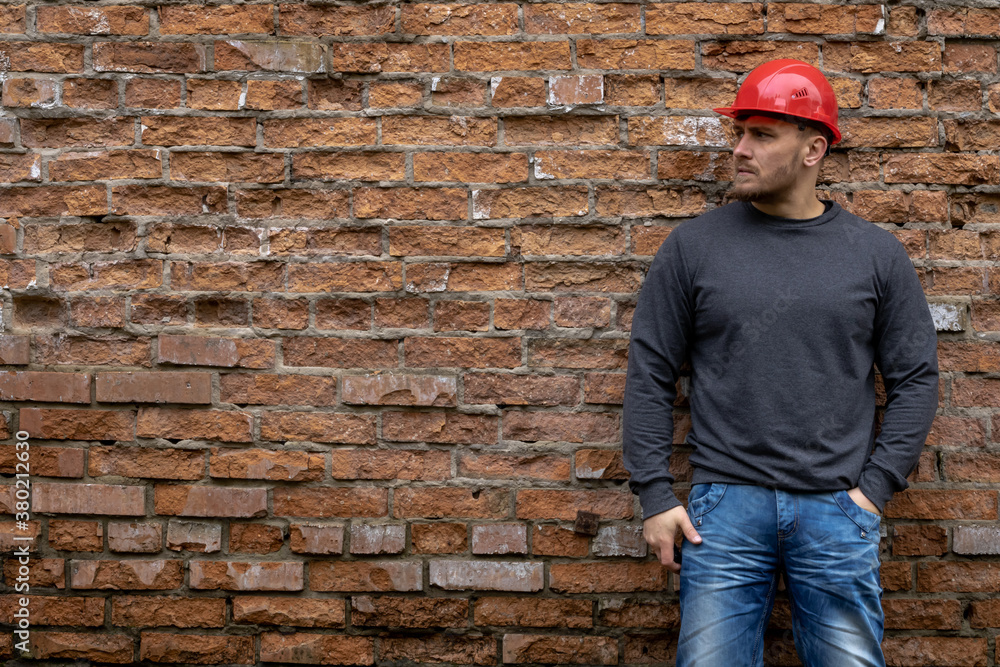 Builder in a hard hat on a brick wall background.