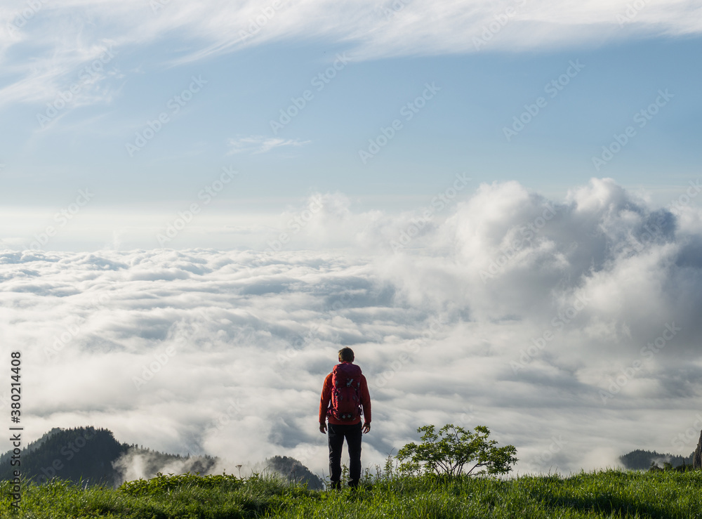 Hiker on top of mountain admiring the sea of clouds Hiker on top of mountain admiring the sea of clouds
