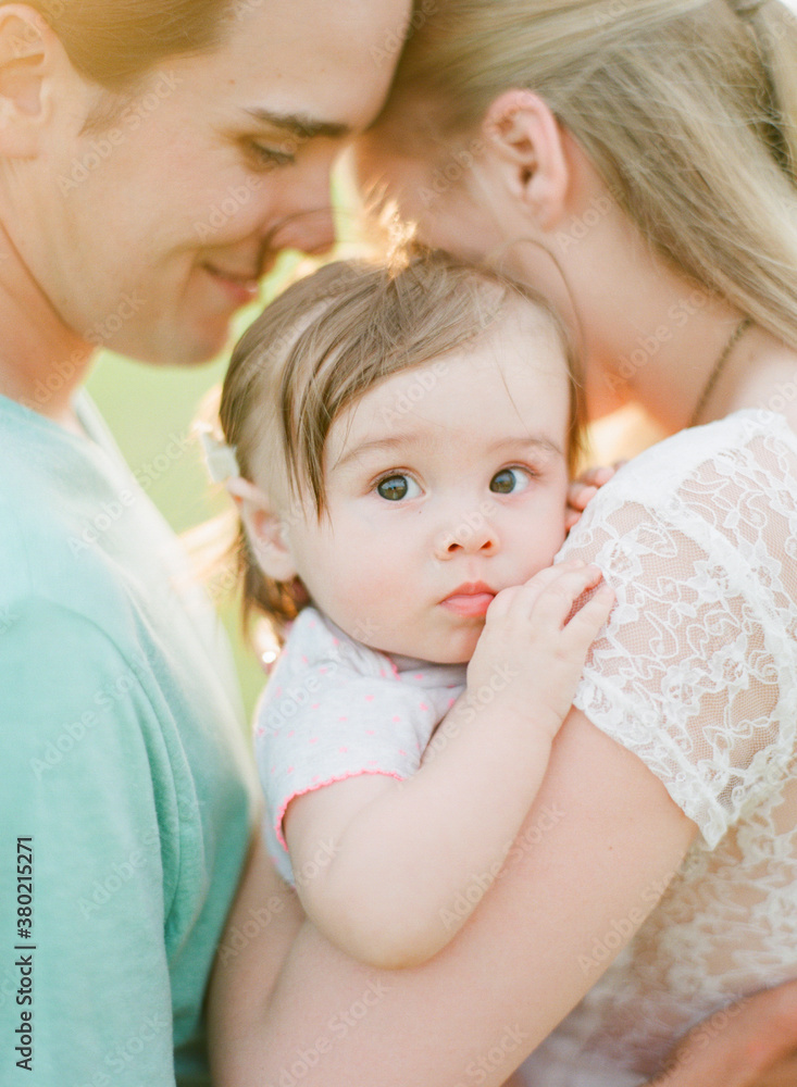 Parents holding their young child close and embracing Parents holding their young child close and embracing