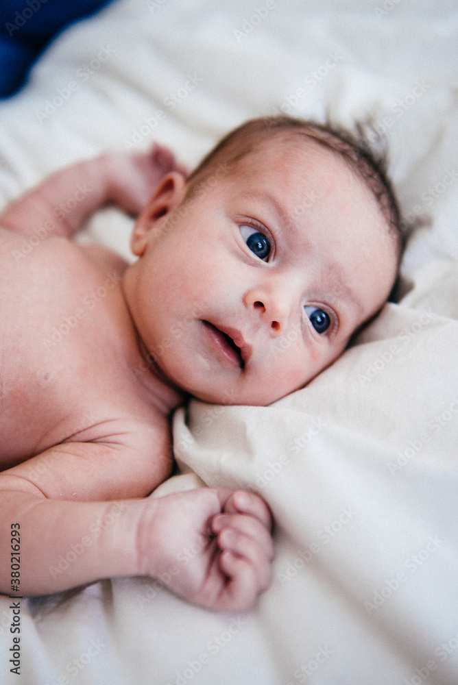 Newborn baby lies on bed, looking around Newborn baby lies on bed, looking around