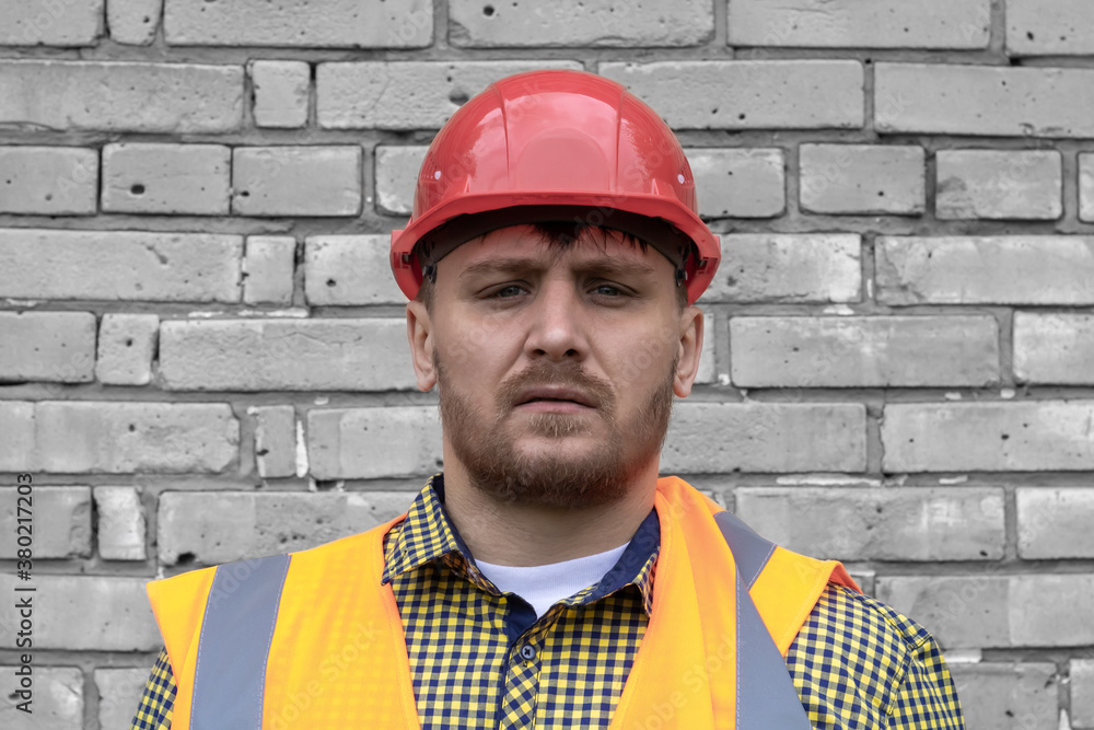 Builder in a hard hat on a brick wall background. Builder in a hard hat on a brick wall background.