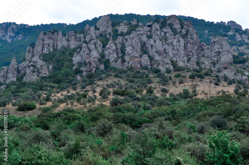 High rock pillars in Valley of Ghosts of the mountain range Demerji, Crimea. Green bushes in the foreground