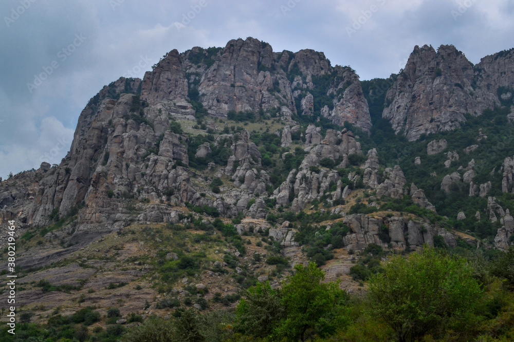 beautiful landscape of quaint stone sculptures formed by weathering of rocks in the Valley of Ghosts on Demerdzhi(Demerji). High mountains. Green bushes in the foreground