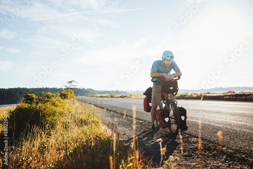 Young, fit man resting from bicycle touring expedition at sunrise photo