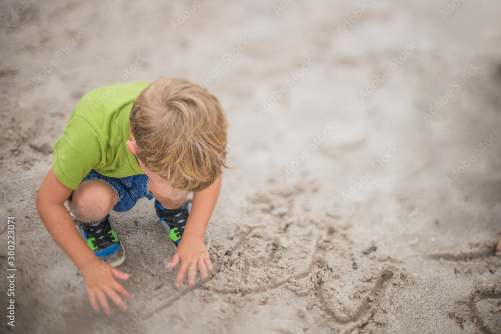 Young Boy Plays on the Playground Drawing in the Sand