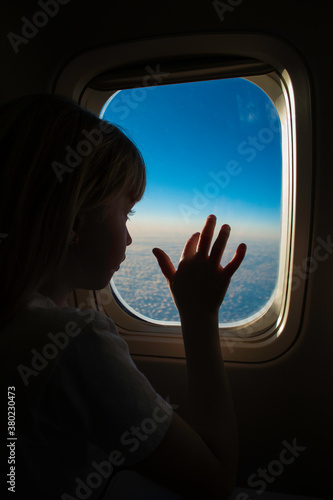 Little Girl Touching Window on Airline Flight on Vacation
