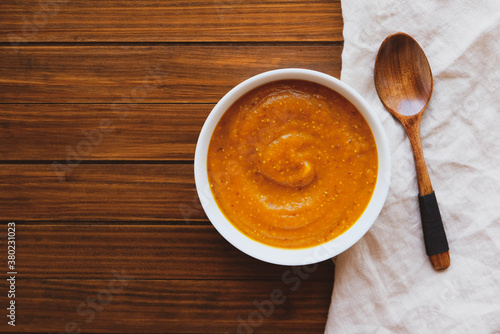 Hot pumpkin soup in a bowl on wooden background.