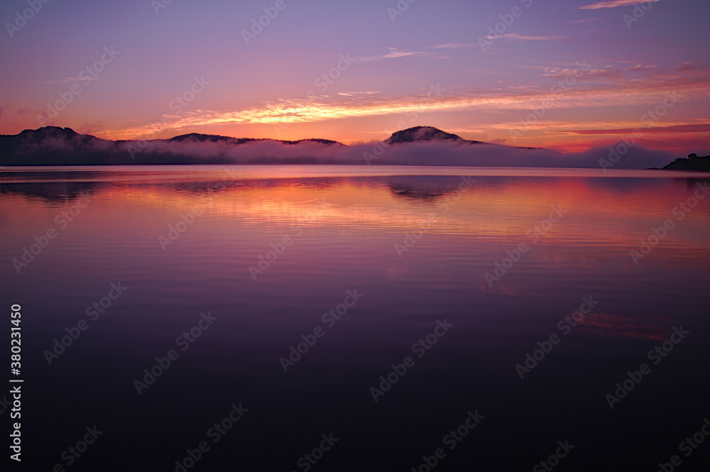 夜明けの空を映す朝の湖。屈斜路湖、北海道。
