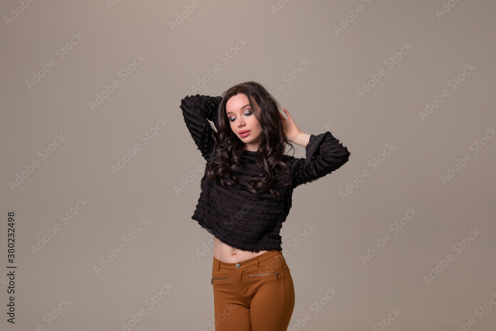 Beautiful young girl smiles and poses on brown beige background. Copy space Beautiful young girl smiles and poses on brown beige background. Copy space