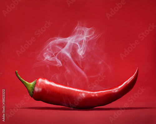Red hot chili pepper on red background with smoke. Still life with steam mexican paprika spice.