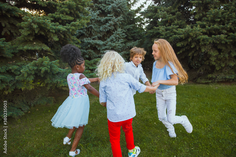 Playing. Interracial group of kids, girls and boys playing together at the park in summer day. Friendship has no race. Happiness, childhood, education, diversity concept. Look happy and sincere.