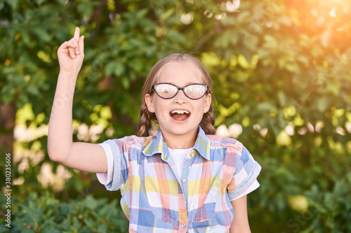 Beautiful american portrait of schoolgirl. Preschool kid. Little happy girl outdoors. Pretty female person. Adorable candid children. Green park. Staycation. Nerd teen. Idea. Looking at camera.