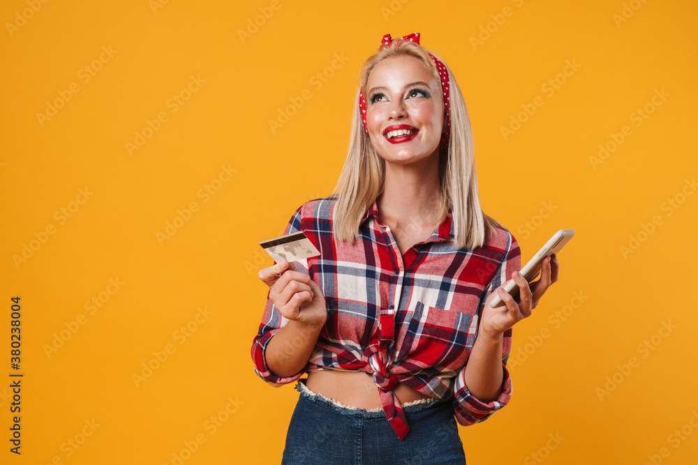 Image of joyful pinup girl posing with credit card and mobile phone Image of joyful pinup girl posing with credit card and mobile phone