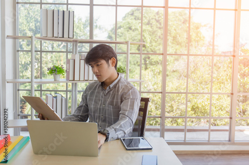 Young Asian men sit and work at a desk in the office.
