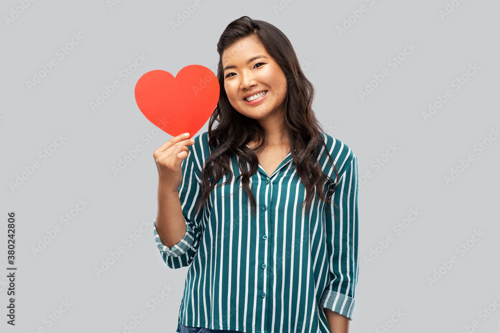 love, charity and valentines day concept - happy asian young woman with red heart over grey background love, charity and valentines day concept - happy asian young woman with red heart over grey background