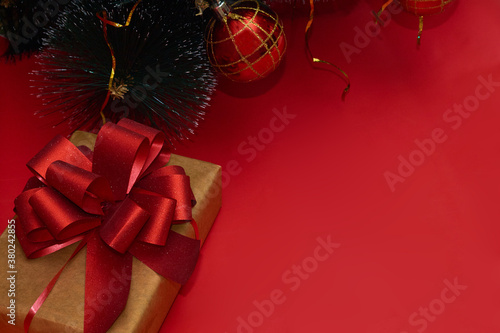 New year or christmas gift a red ribbon under tree with red balls on red background, copy space