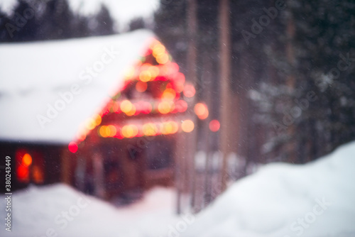 Holiday lights on a ski cabin surrounded by deep snow and pine trees photo