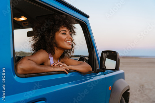 Image of cheerful african american woman smiling while travelling in car photo