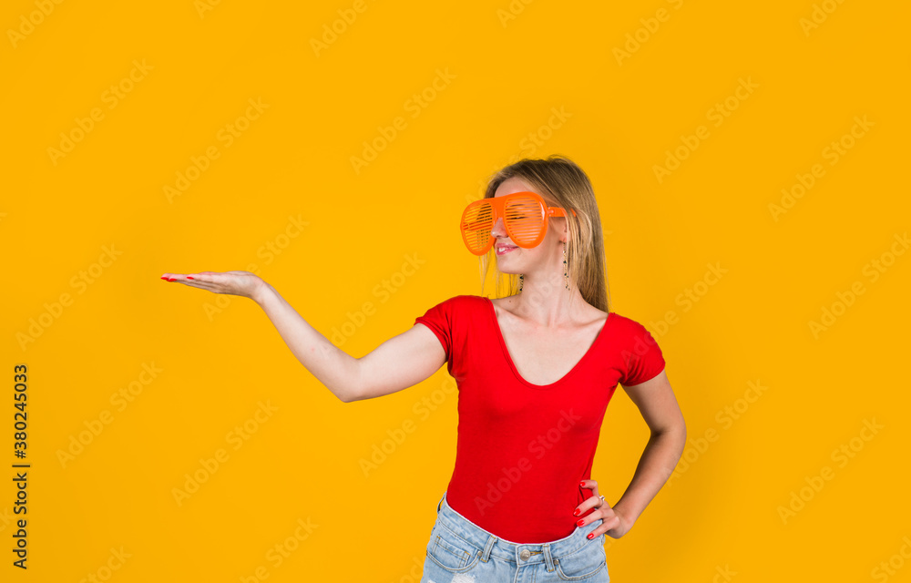 Advertising. Woman holds something. Look over here! Add. Sales and discount. Season sale. Funny woman pointing away. Advertising. Woman holds something. Look over here! Add. Sales and discount. Season sale. Funny woman pointing away.