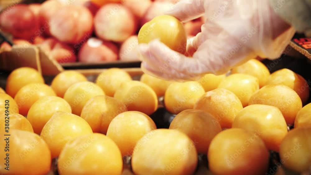 Customer chooses plums at the food market. Hands of customer in gloves close-up. Customer chooses plums at the food market. Hands of customer in gloves close-up.