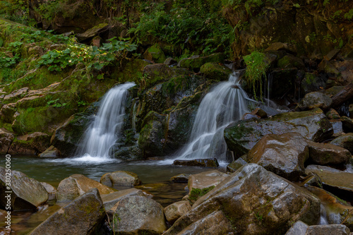 Magical mountain waterfall  crystal water  large stones overgrown with moss. The waterfall with the crystal clear water that flows quickly. Waterfall on the Kamyanka River  Skole Beskydy Nature Park.